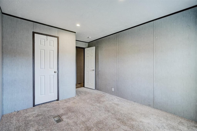 unfurnished bedroom with a textured ceiling and light colored carpet