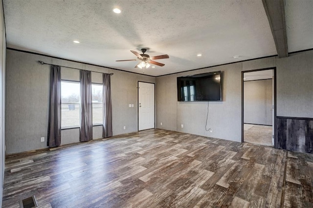 unfurnished living room with hardwood / wood-style flooring, ceiling fan, beam ceiling, and a textured ceiling