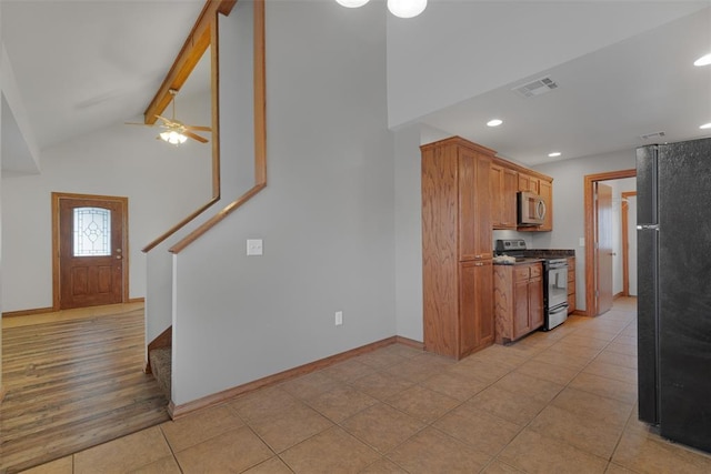 kitchen with vaulted ceiling with beams, ceiling fan, stainless steel appliances, and light hardwood / wood-style flooring