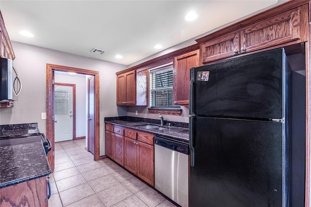 kitchen with sink, light tile patterned floors, stainless steel appliances, and dark stone counters