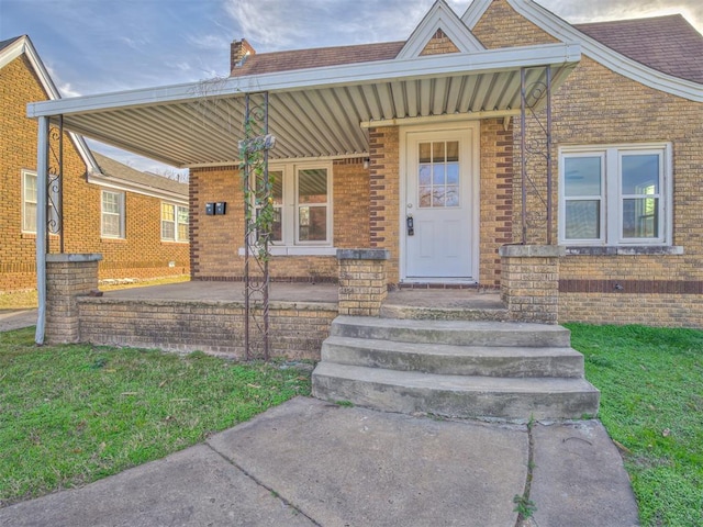 view of exterior entry with a porch and a lawn