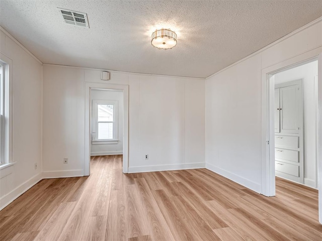 unfurnished room featuring ornamental molding, a textured ceiling, and light wood-type flooring