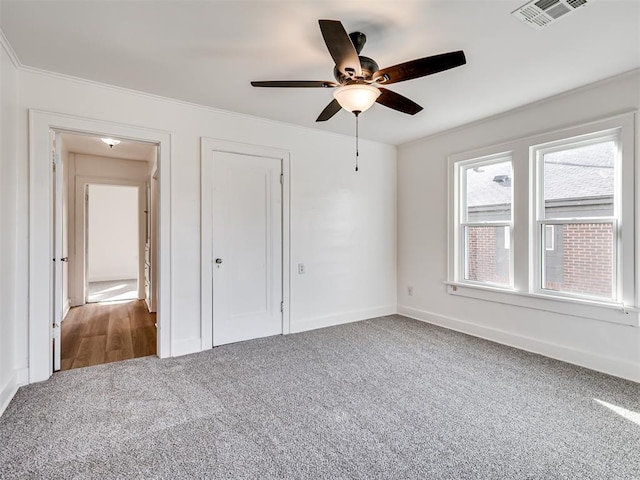 unfurnished bedroom featuring ceiling fan, carpet floors, and ornamental molding