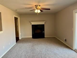 unfurnished living room featuring carpet floors and ceiling fan