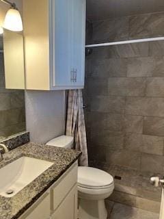 bathroom featuring vanity, toilet, and tiled shower