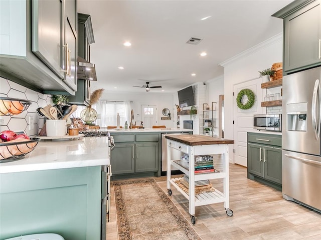 kitchen featuring appliances with stainless steel finishes, a sink, green cabinets, and tasteful backsplash