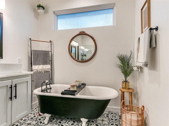 full bathroom featuring a soaking tub, tile patterned flooring, baseboards, and vanity