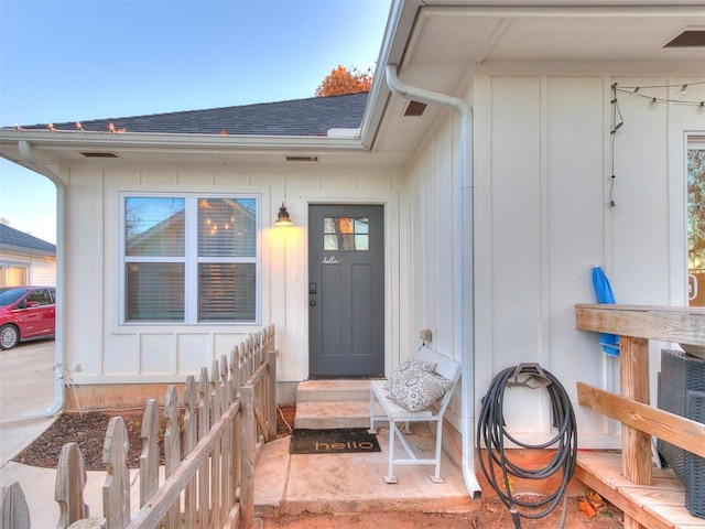 doorway to property featuring roof with shingles and board and batten siding