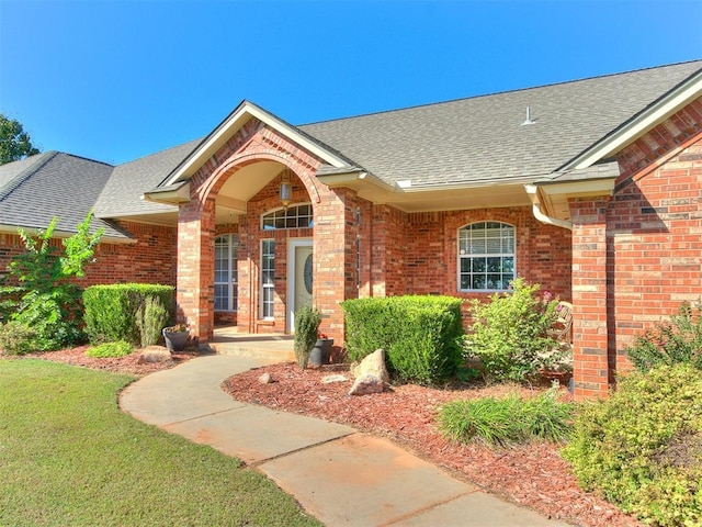 826 S Mustang Rd, Tuttle, OK 73089 - doorway to property with roof with shingles, brick siding, and a yard