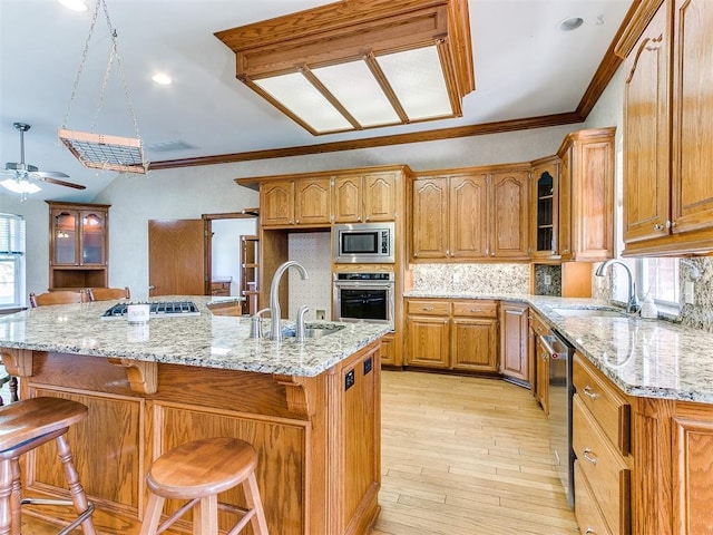 826 S Mustang Rd, Tuttle, OK 73089 - kitchen featuring appliances with stainless steel finishes, tasteful backsplash, a ceiling fan, brown cabinets, and light stone countertops