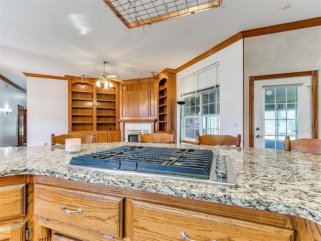 826 S Mustang Rd, Tuttle, OK 73089 - kitchen with crown molding, stainless steel gas cooktop, a fireplace, ceiling fan, and light stone countertops