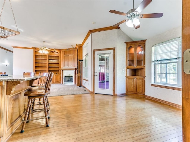 826 S Mustang Rd, Tuttle, OK 73089 - kitchen with ceiling fan, built in shelves, a fireplace, ornamental molding, and a breakfast bar area
