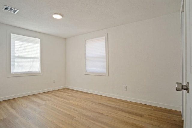 spare room with light hardwood / wood-style flooring and a textured ceiling