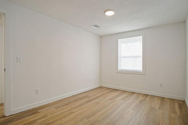 empty room featuring a textured ceiling and light wood-type flooring