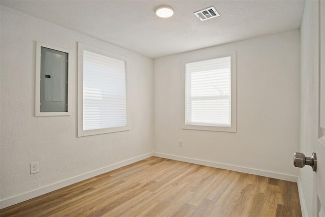 unfurnished room with electric panel and light wood-type flooring