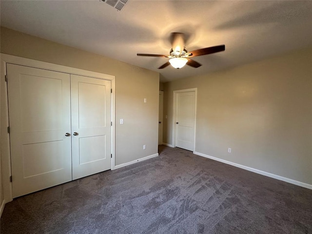 unfurnished bedroom with dark colored carpet, ceiling fan, and a closet