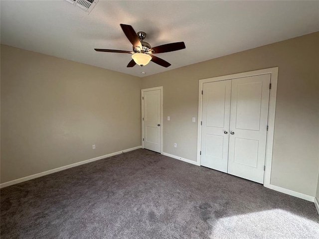 unfurnished bedroom featuring dark carpet, a closet, and ceiling fan