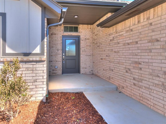 property entrance featuring visible vents and brick siding