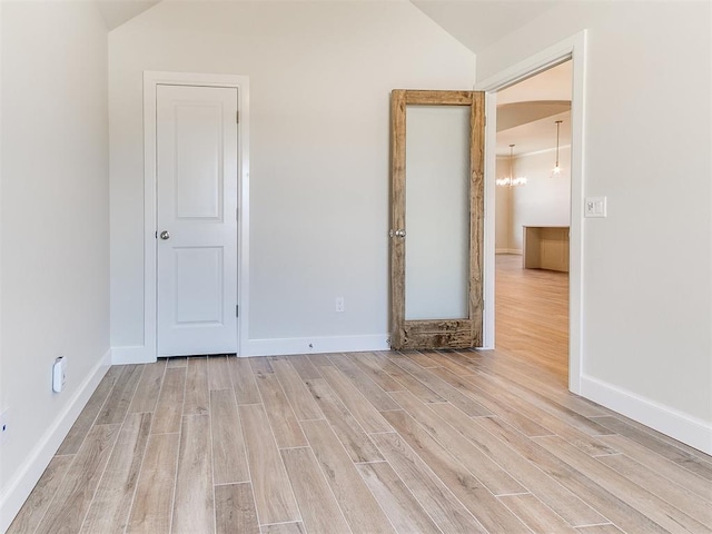 unfurnished bedroom featuring lofted ceiling, wood finished floors, and baseboards