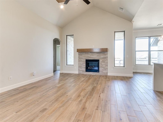 unfurnished living room featuring arched walkways, visible vents, light wood-type flooring, and a glass covered fireplace