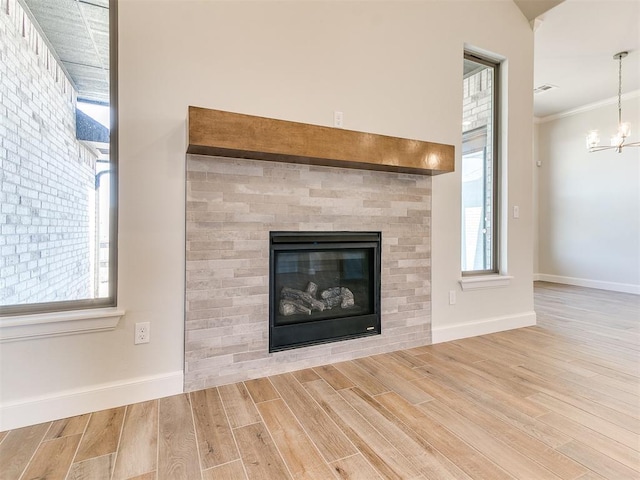 details with crown molding, baseboards, a chandelier, wood finished floors, and a glass covered fireplace