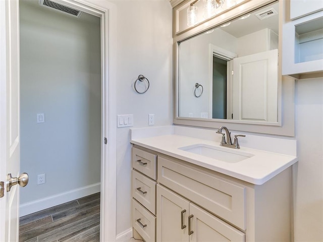 bathroom featuring visible vents, baseboards, wood finished floors, and vanity