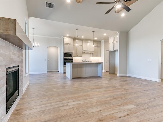 kitchen with visible vents, open floor plan, ceiling fan with notable chandelier, appliances with stainless steel finishes, and a fireplace