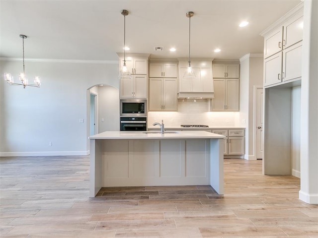 kitchen with light wood-type flooring, a sink, stainless steel appliances, arched walkways, and decorative backsplash