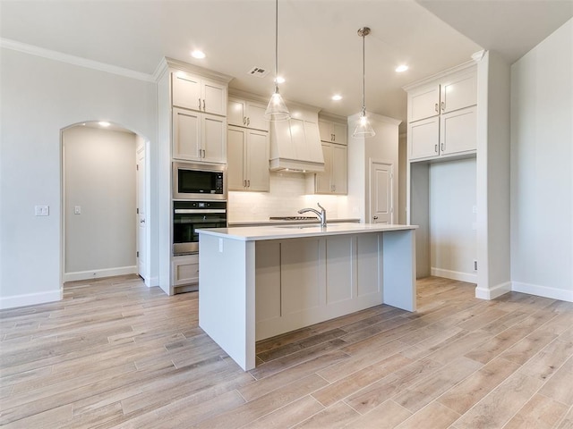 kitchen with visible vents, arched walkways, stainless steel appliances, decorative backsplash, and light wood-type flooring