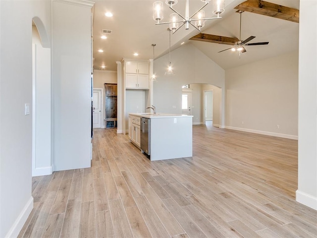 kitchen with a ceiling fan, light wood-type flooring, arched walkways, stainless steel dishwasher, and open floor plan