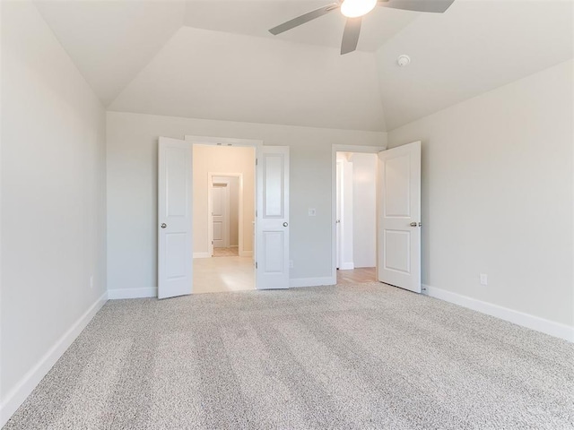 unfurnished bedroom featuring light carpet, baseboards, lofted ceiling, and a ceiling fan