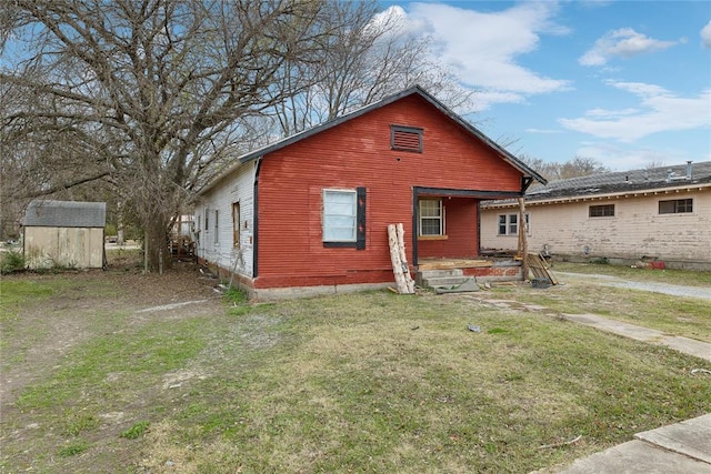 back of house with a lawn and a shed