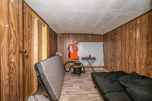 living area featuring a textured ceiling, light hardwood / wood-style flooring, and wood walls