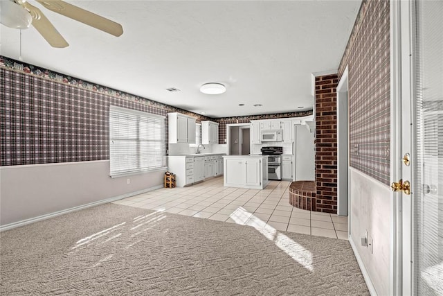 kitchen featuring white appliances, light carpet, sink, ceiling fan, and white cabinetry