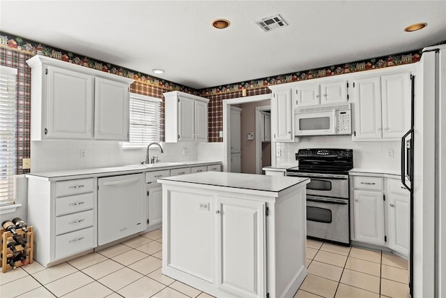 kitchen with white appliances, white cabinets, sink, light tile patterned floors, and a kitchen island