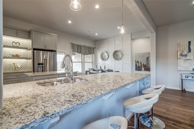 kitchen featuring pendant lighting, sink, stainless steel fridge, gray cabinets, and dark hardwood / wood-style flooring