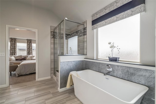 bathroom featuring plenty of natural light, wood-type flooring, vaulted ceiling, and shower with separate bathtub