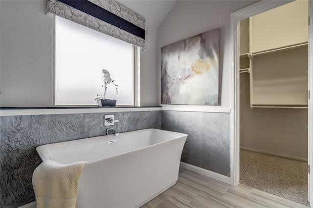 bathroom featuring hardwood / wood-style flooring, a bathtub, and lofted ceiling