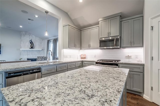 kitchen with sink, vaulted ceiling, light stone counters, dark hardwood / wood-style flooring, and stainless steel appliances