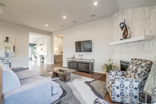 living room with lofted ceiling, a large fireplace, and wood-type flooring