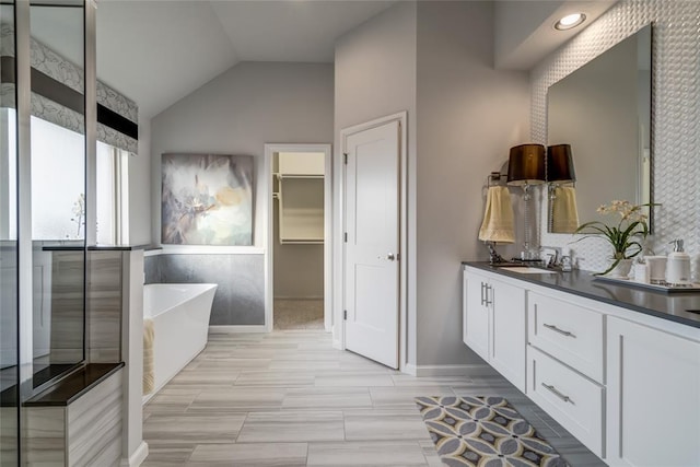 bathroom with a washtub, vanity, and vaulted ceiling