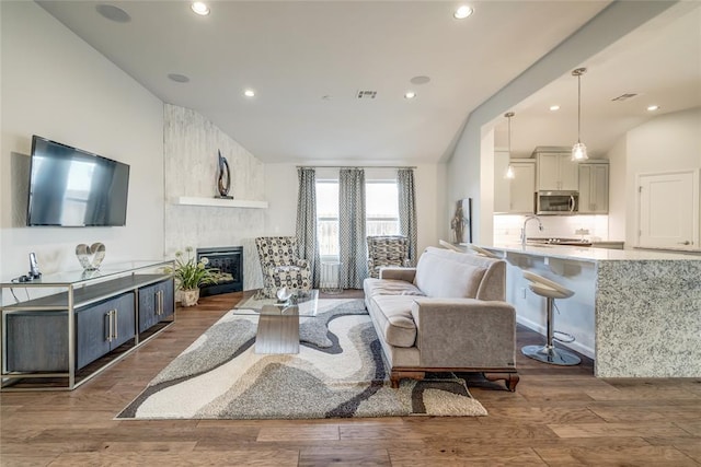 living room with a large fireplace, dark wood-type flooring, and lofted ceiling