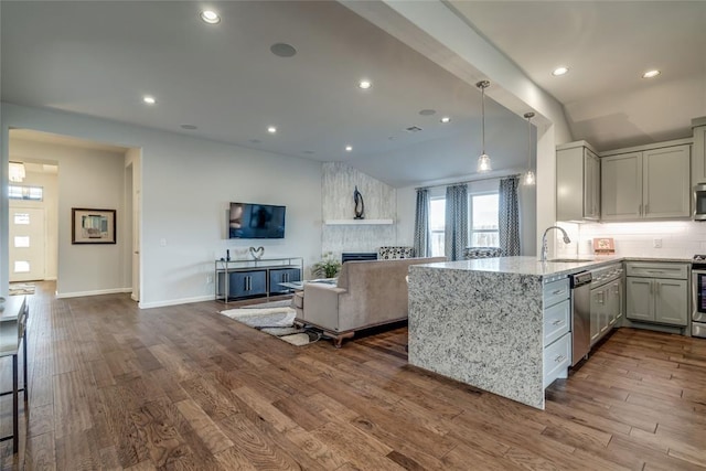 kitchen with sink, light hardwood / wood-style flooring, a large fireplace, kitchen peninsula, and stainless steel appliances