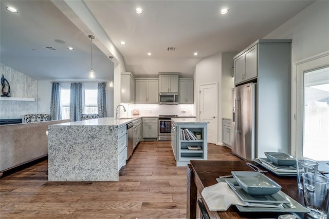 kitchen featuring hardwood / wood-style floors, kitchen peninsula, plenty of natural light, and stainless steel appliances