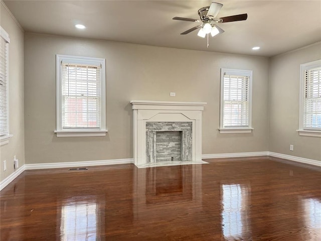 unfurnished living room with plenty of natural light, dark hardwood / wood-style floors, a fireplace, and ceiling fan