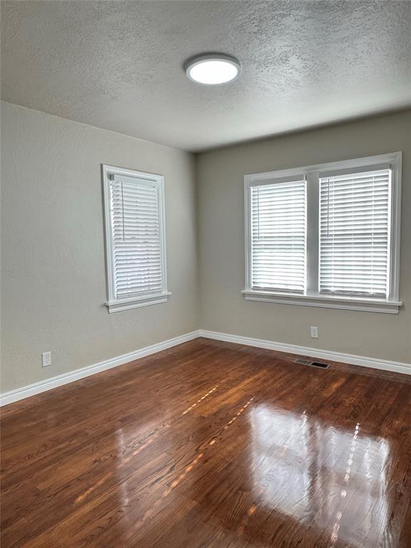 unfurnished room featuring a textured ceiling and dark hardwood / wood-style flooring