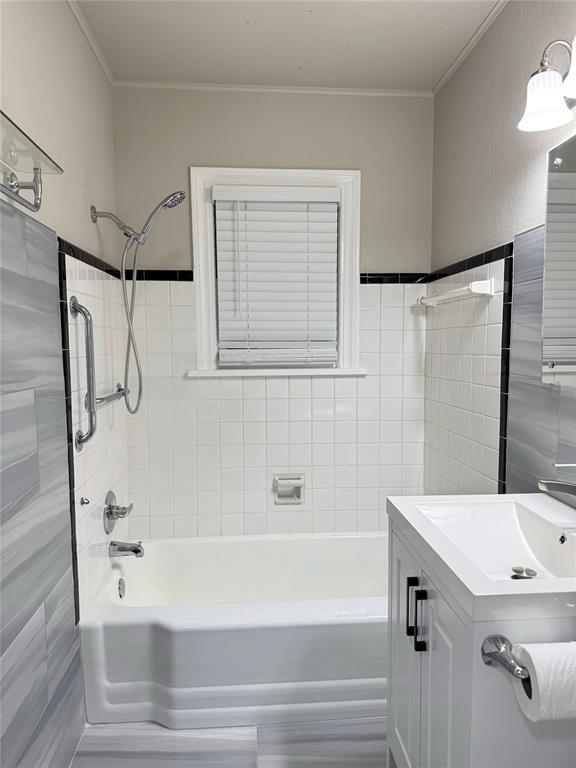 bathroom featuring  shower combination, vanity, tile walls, and ornamental molding