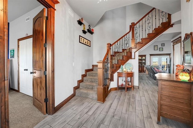 stairway featuring french doors, high vaulted ceiling, and hardwood / wood-style flooring