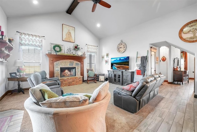 living room with plenty of natural light, beam ceiling, a fireplace, and ceiling fan