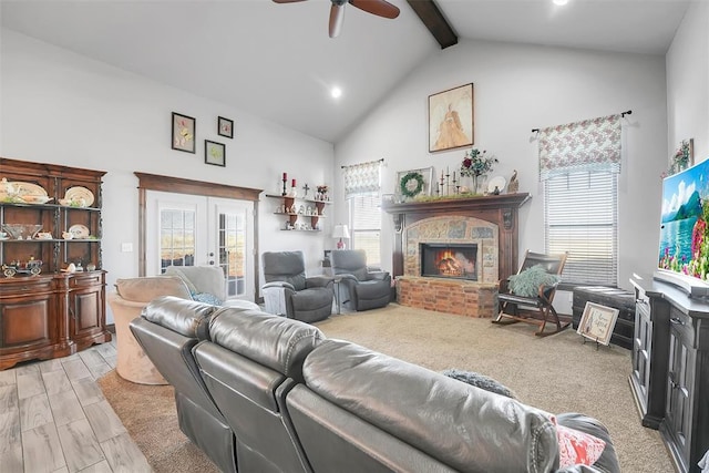 living room with beam ceiling, a fireplace, a healthy amount of sunlight, and light hardwood / wood-style flooring